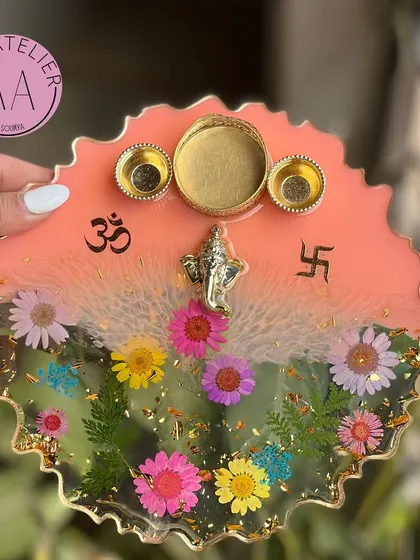 This handmade resin pooja thali, decorated with real preserved flowers and sacred icons, is designed to bring so much beauty to your sacred rituals. This piece features a lovely peach and floral design with a Ganesh idol.