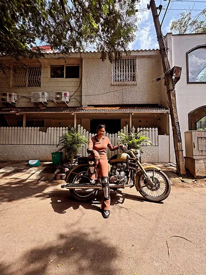 A graduate poses with her bike in a stylish outfit. Riding is an expression of personality, and she wears it well.