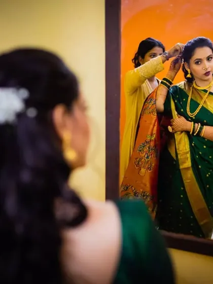 A behind-the-scenes moment, capturing me putting the finishing touches on the bride's floral bun. The mirror reflection shows the complete look coming together.