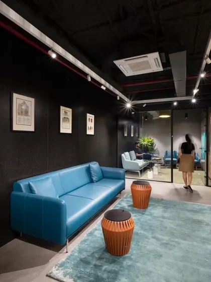 An executive lounge with a sleek blue leather sofa and dark walls. The space is designed to be a quiet, sophisticated retreat.