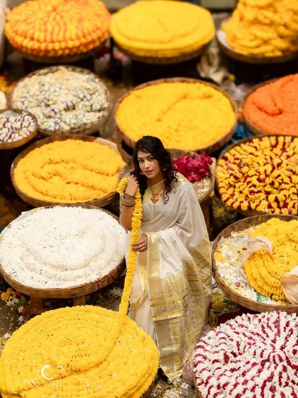 A beautiful portrait where she is surrounded by baskets of flowers. The colors are vibrant, and her presence is serene and graceful.