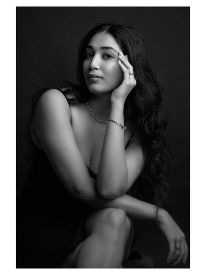 A moody and introspective black and white portrait. The model's pose and the soft lighting create a beautiful and emotional image.