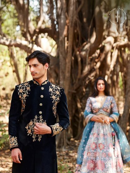 A candid moment from a wedding shoot. The groom, in a striking black and gold sherwani, glances back at his bride. This is the kind of cinematic style I help create for your big day.