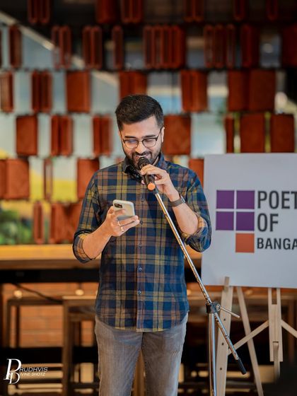 A poet reads from his phone, a familiar and relatable scene at our modern open mics. The focus is always on the words and the story being told.