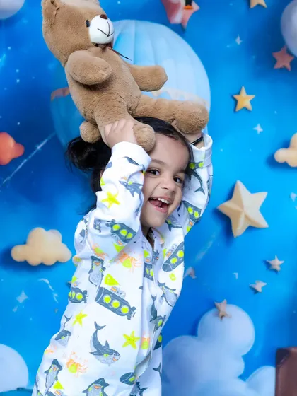 A moment of pure fun as a child plays with a teddy bear during a sibling photoshoot.