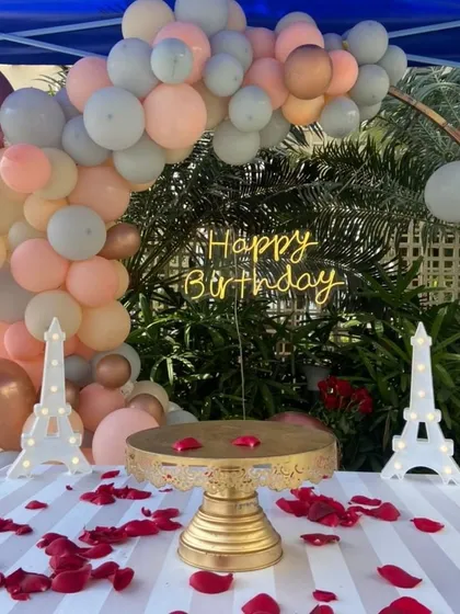 We create intimate and romantic settings for your most personal celebrations. This beautiful outdoor birthday surprise features a custom balloon garland, elegant Eiffel Tower props, and a perfectly set cake table with scattered rose petals.