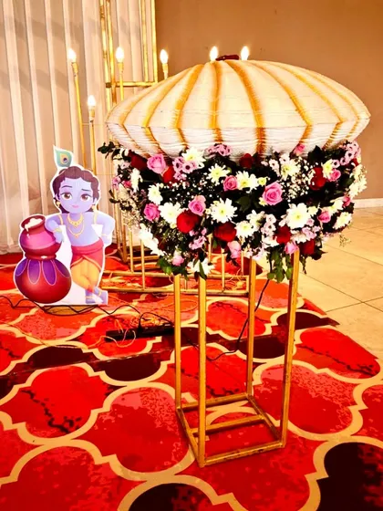 A Krishna-themed naming ceremony featuring a cute cutout of little Krishna and a floral arrangement designed to look like a traditional umbrella.