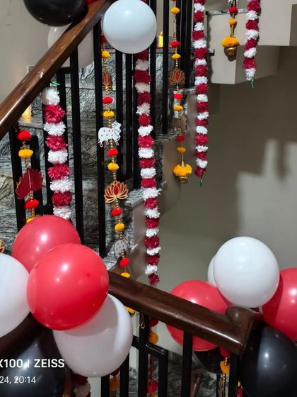 A staircase decorated for Diwali with traditional hangings and a balloon arrangement in red, white, and black.