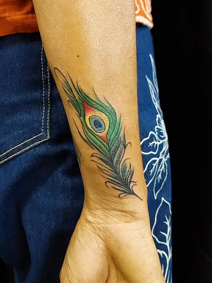We covered up an old name tattoo with this colorful peacock feather. The rich greens and blues completely hide the old ink, replacing it with a symbol of beauty.