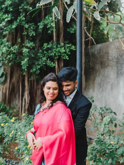 A close-up of a loving embrace amidst greenery, focusing on the couple's happy expressions and connection.
