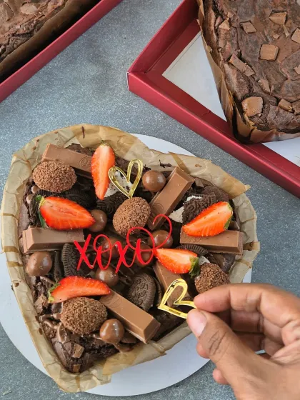 Decorating a heart-shaped brownie with cute "XOXO" and heart toppers. These little details make each gift box feel extra special.