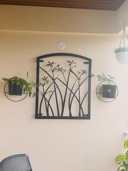 This creative wall decor combines metal art with live plants. The simple black planters with trailing plants frame the dragonfly art, turning the wall into a unique and beautiful feature.