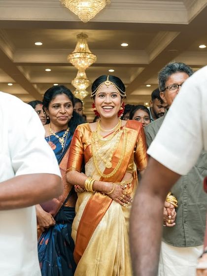 The bride's joyful entrance at her South Indian wedding, accompanied by traditional music and her loving family.