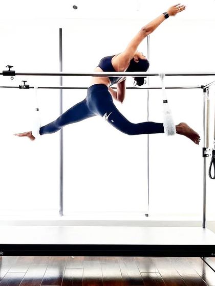 A client demonstrates a flying split on the Cadillac. This advanced move showcases incredible flexibility and strength, a true testament to the power of Pilates.