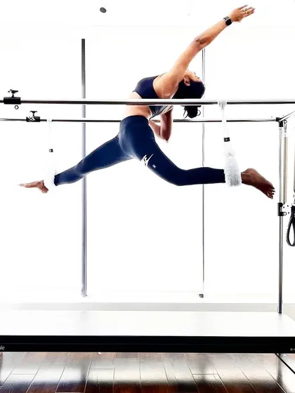 A client demonstrates a flying split on the Cadillac. This advanced move showcases incredible flexibility and strength, a true testament to the power of Pilates.