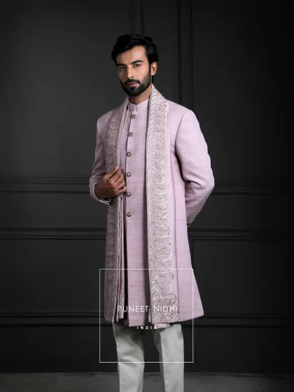 This pastel lavender Achkan in fine silk is tailored in a straight silhouette. The embroidered stole with intricate paisley motifs elevates the look for understated luxury.