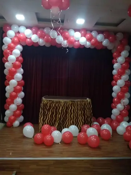 A red and white balloon arch set up on a stage. This provides a simple yet effective backdrop for presentations, award ceremonies, or performances during a corporate event.
