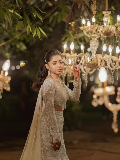 The bride, illuminated by the warm glow of chandeliers. This portrait captures her elegance and the magical ambiance of the evening celebration.