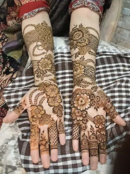 A lovely shot of a full-coverage floral mehendi design, featuring delicate hanging chains and bell motifs on the wrist.