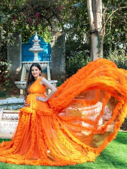 A dramatic "flying fabric" shot of our orange ruffled gown in a beautiful garden setting, creating a stunning visual.
