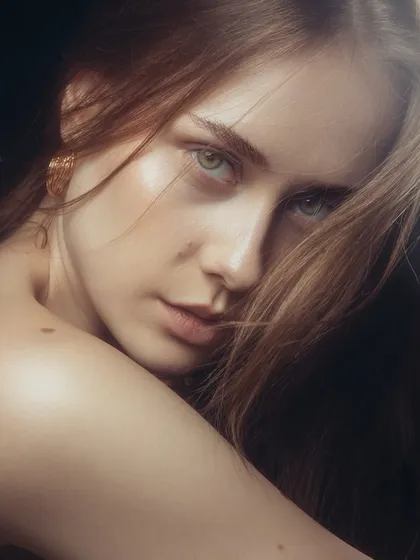 This intimate close-up shows the power of a 'no-makeup' makeup look. The skin has a natural sheen, brows are lightly groomed, and the focus is entirely on the model's expressive eyes.
