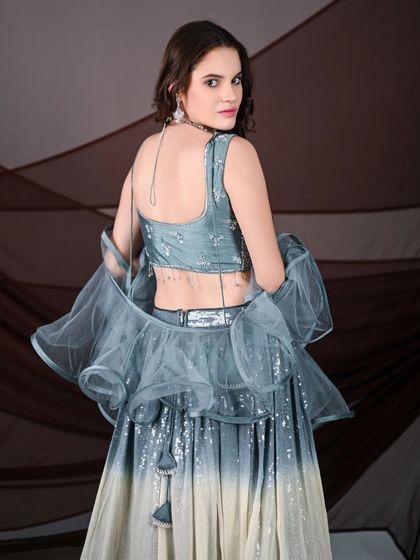 A view of the back of the grey ombre lehenga, showing the stylish blouse design and the delicate ruffled dupatta. It’s a modern and chic option for any photoshoot.