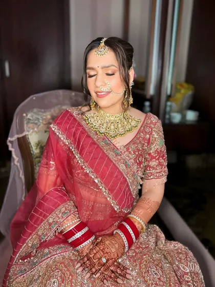 A full view of the bride in her stunning red lehenga. The hair and makeup are designed to be timeless and photograph beautifully, ensuring she looks her best on her special day.