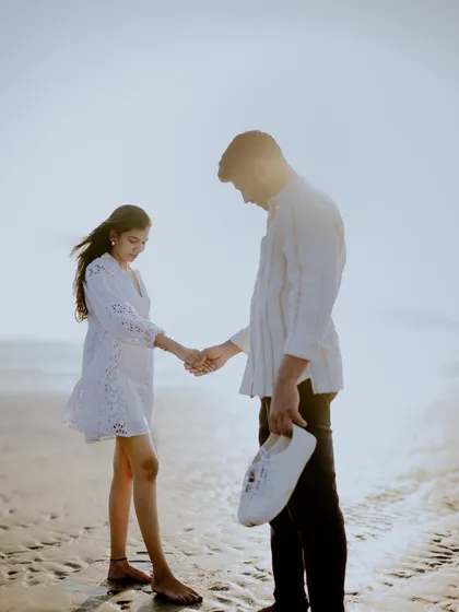 A quiet, thoughtful moment on the beach. The groom holding his shoes and their gentle handhold tell a story of a peaceful walk by the sea.