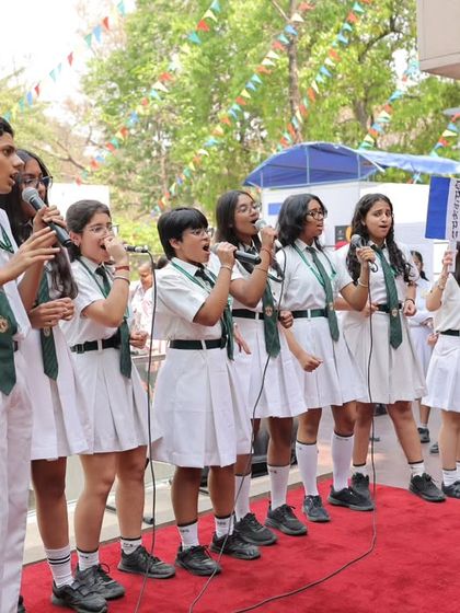 School children in uniform sing on stage, holding French flags during the Francophonie Mela. We love involving young learners in our celebrations, fostering a passion for French culture from an early age.