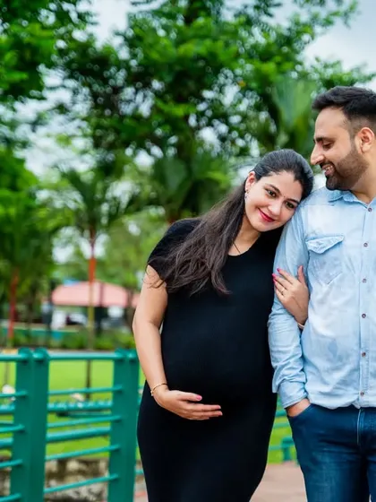 A gentle walk through the park. The mom-to-be rests her head on her partner's shoulder, a simple gesture of love and support.