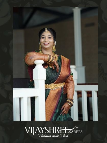 A beautiful client draped in a dark green Kanjivaram with a contrasting rust-colored border, perfect for a wedding guest look.