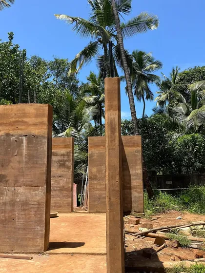 The completed rammed earth walls stand tall against the Goan sky, with the beautiful striations of the compacted earth clearly visible.