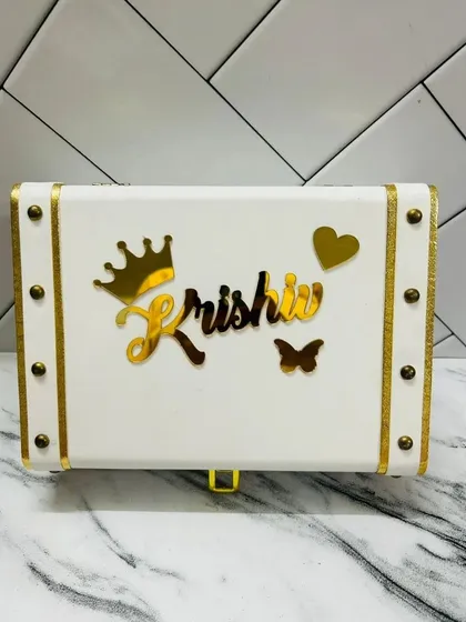 A classic white trunk box, personalized with a name and charms. The clean look of the white leatherette makes the gold details stand out beautifully.