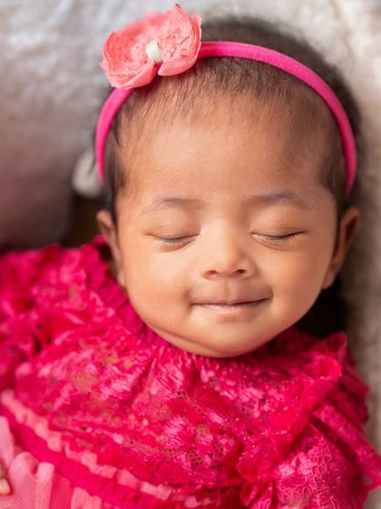A beautiful smiling baby girl in a vibrant pink dress. I capture both sleeping and awake moments, showcasing your baby's budding personality.