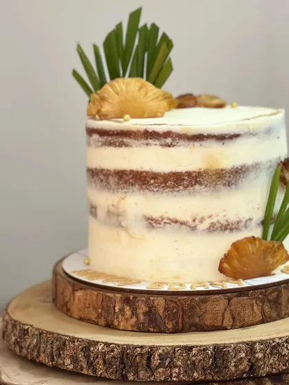 A vintage-style semi-naked cake for a birthday. The exposed layers and simple decoration with dried pineapple give it a lovely rustic charm.
