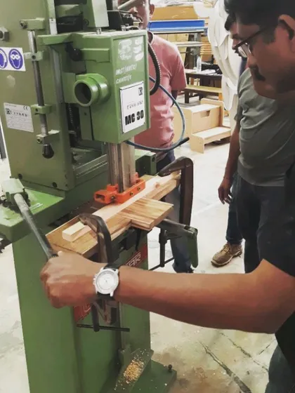 A student operates the mortising machine, which uses a chisel and drill bit to quickly create clean, square mortises for strong furniture frames.