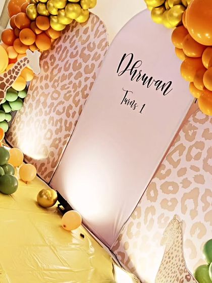 A tilted view of a jungle theme, focusing on the leopard-print backdrop panels and the rich, textured balloon clusters in orange and green.