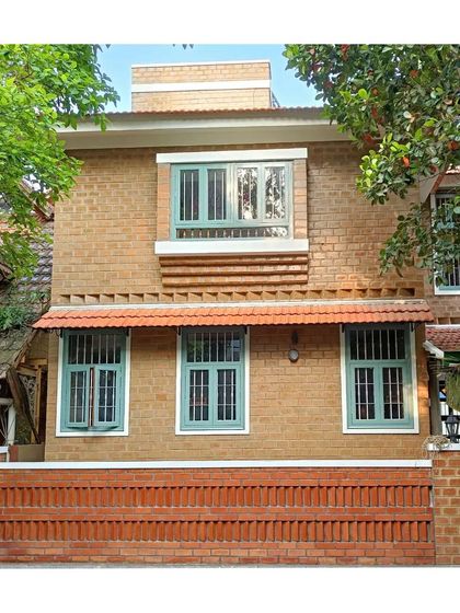The facade of the Surbhi and Deepak residence in Bangalore, featuring walls of soil cement blocks and contrasting light green window frames.