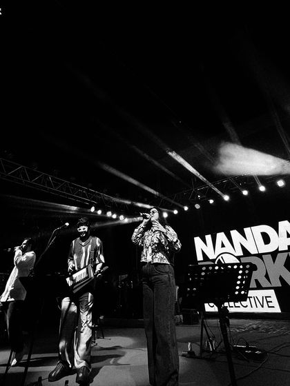 A dramatic black and white shot of the band on stage, with the "Nandan Borker Collective" branding visible. It highlights the collective effort that goes into our shows.