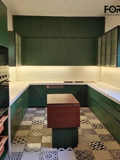 A stunning U-shaped kitchen in a bold matte green finish. This design features a movable central island for flexible prep space, patterned floor tiles, and integrated under-cabinet lighting, creating a perfect balance of modern style and classic charm.