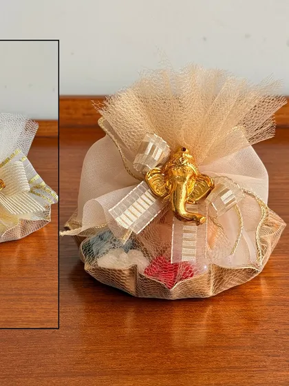 A close-up of our festive potli gift, featuring a small candle and other trinkets, adorned with a golden Ganesha charm. It's a perfect small token for Diwali or Ganesh Chaturthi.