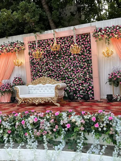 The full stage setup, showing the balance between the floral backdrop, the elegant furniture, and the soft drapery.