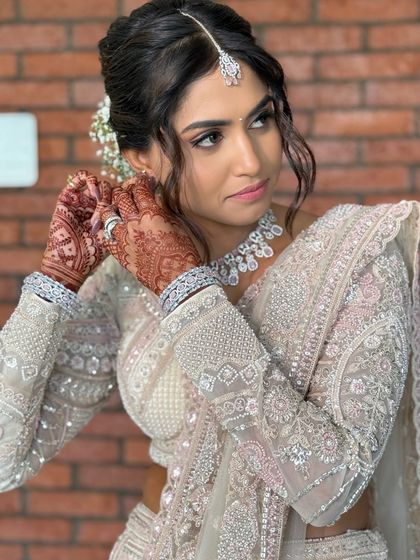 A candid moment of the bride adjusting her earring, showcasing the detailed henna and the flawless makeup.