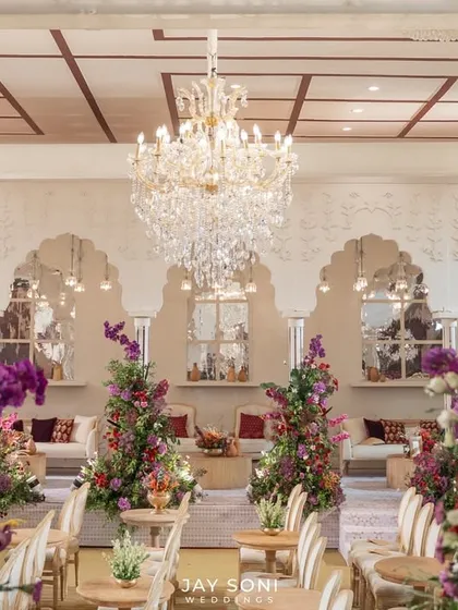 Looking through an archway into the main lounge space, where a grand crystal chandelier hangs above elegant seating arrangements, creating a sense of opulence and grandeur.