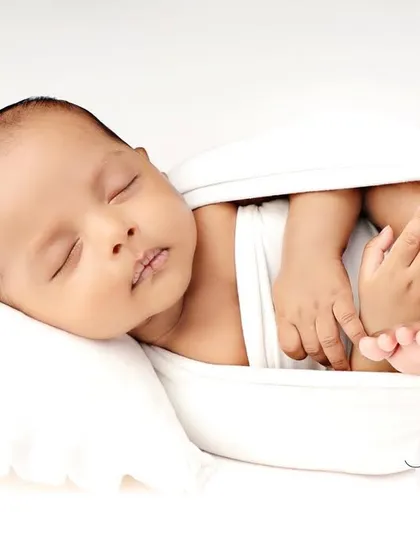 A full-body shot of the baby in the white 'potato sack' pose, looking like they are floating on a cloud.