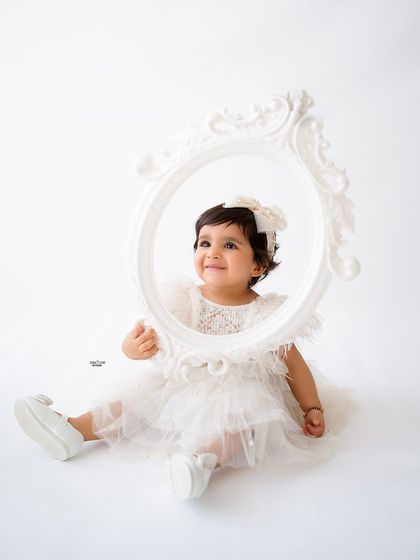 Peeking through a beautiful white frame, this little angel is picture-perfect.