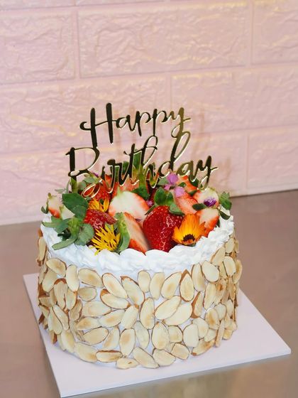 Strawberries on top make everything better. This beautiful birthday cake is covered in toasted almonds and topped with fresh strawberries and flowers.