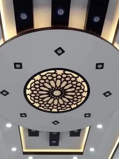 A circular ceiling with a beautiful 'jaali' cutout in the center. The warm backlighting makes the intricate pattern stand out.