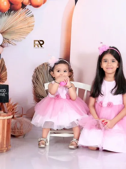 A stylish sisters photoshoot with a modern boho theme. The pink dresses and balloon decorations create a chic and celebratory setting for this lovely sibling portrait.