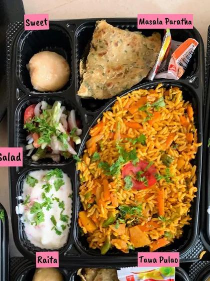 A satisfying meal plate featuring Tawa Pulao, Masala Paratha, fresh salad, cool raita, and a homemade sweet.